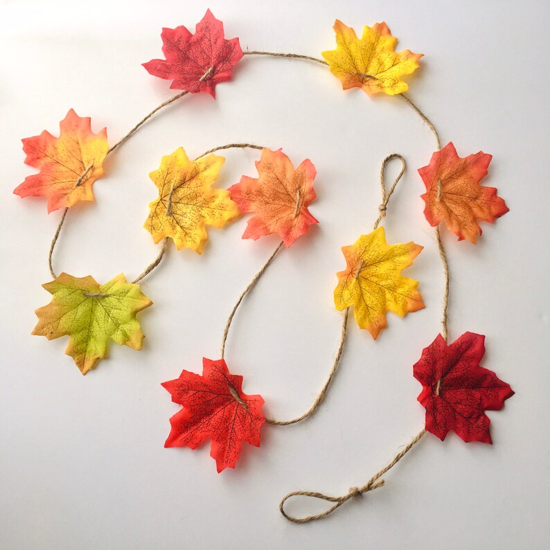 May include: A fall-themed garland with a string of faux leaves in shades of red, orange, and yellow.