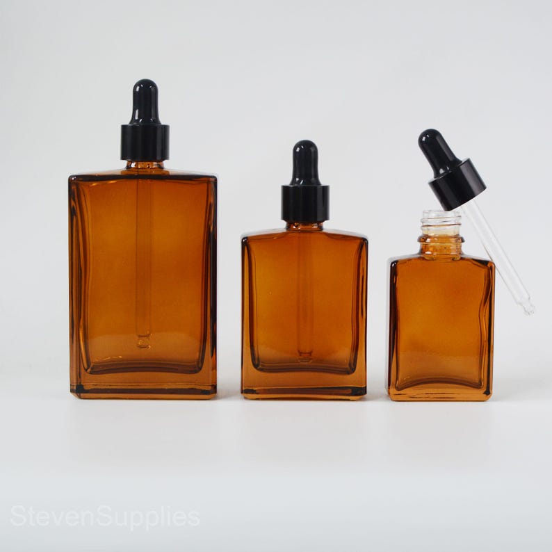 May include: Three amber glass bottles with black dropper tops. The bottles are square shaped and come in three sizes.