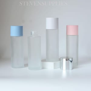 Pode incluir: Quatro frascos de vidro fosco com tampas coloridas e uma tampa prateada. As tampas são azul claro, brancas e rosa. Os frascos são cilíndricos e parecem vazios. O texto "STEVENSUPPLIES" está na parte superior da imagem.