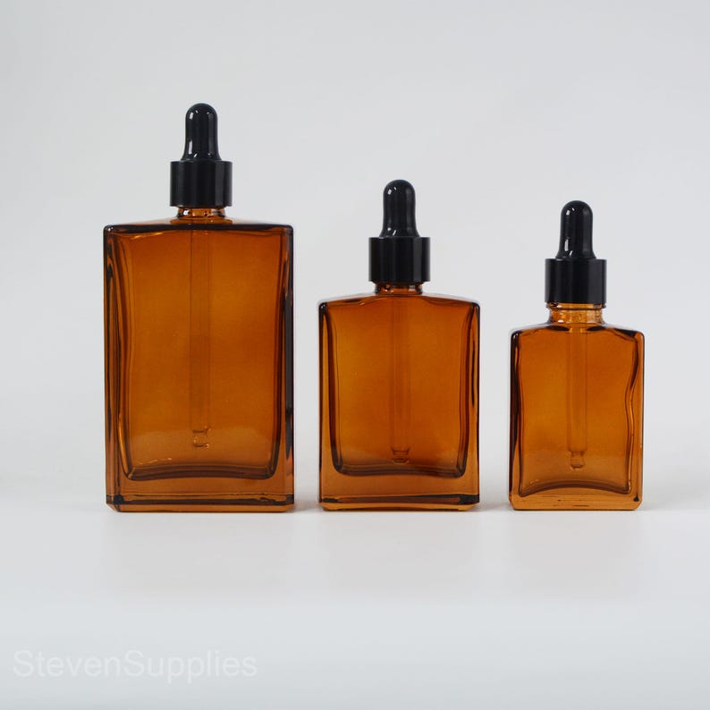 May include: Three amber glass bottles with black dropper tops. The bottles are different sizes and are arranged from largest to smallest.