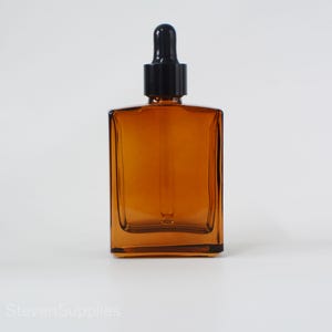 May include: Amber glass dropper bottle with a black dropper cap. The bottle is square shaped and has a clear glass body.