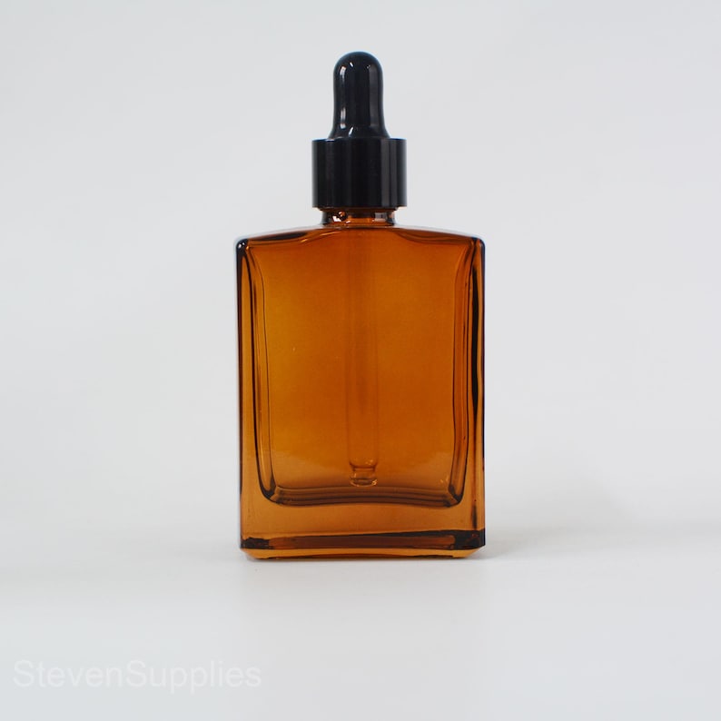 May include: Amber glass dropper bottle with a black dropper cap. The bottle is square shaped and has a clear glass body.