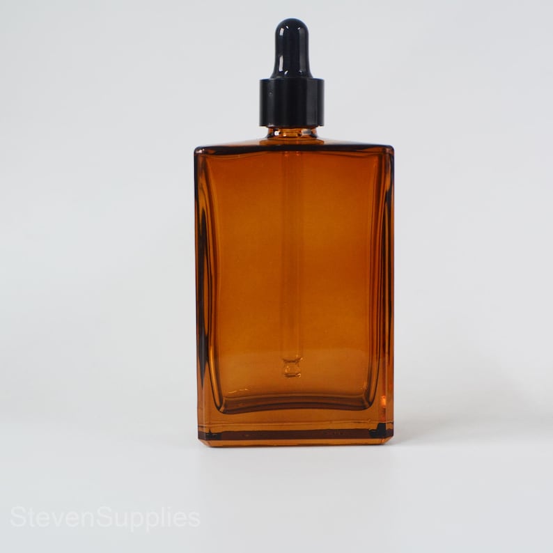 May include: Amber glass bottle with a black dropper top. The bottle is rectangular and has a square base.