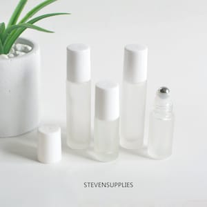 May include: Five frosted glass roller bottles with white caps. Four bottles have a standard roller ball, and one bottle has a metal roller ball.