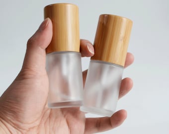 May include: Two frosted glass bottles with bamboo caps. The bottles are clear and have a frosted finish. The caps are made of natural bamboo.