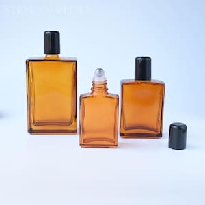 May include: Three rectangular amber glass bottles with black caps. Two bottles are capped, while one central bottle features a silver roller ball top. The text STEVENSSUPPLIES is visible in the upper left corner of the image.