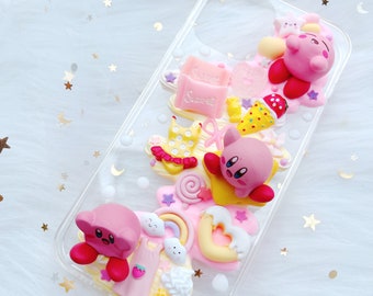 May include: A clear phone case with a pink, yellow, and white 3D design. The design features a pink character with a star, a pink character with a heart, a pink character with a dress, and a pink character with a lollipop. The case also has a pink and white candy bar with the word "Sweet" on it.