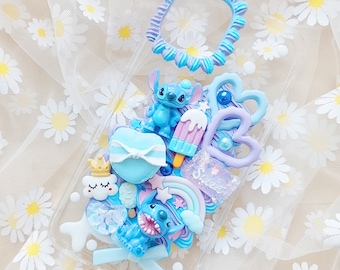 May include: A clear phone case decorated with blue and purple 3D embellishments, including Stitch characters, a rainbow, a cloud, a heart, and a popsicle. The case also features the word "Sweet" in purple glitter.