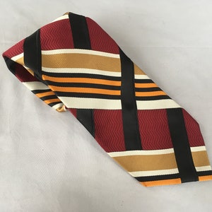 Mens wide 1970s polyester tie, heavy thick and ugly, with burgundy, orange, black and gold woven pattern, 4 inch wide tie