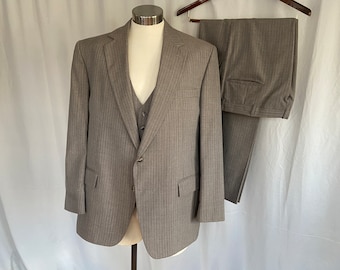May include: A gray pinstripe suit with a matching vest. The suit jacket has a single button closure and a notched lapel. The vest has a V-neck and four buttons.