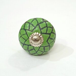May include: Green ceramic cabinet knob with a black geometric pattern and a silver metal center.