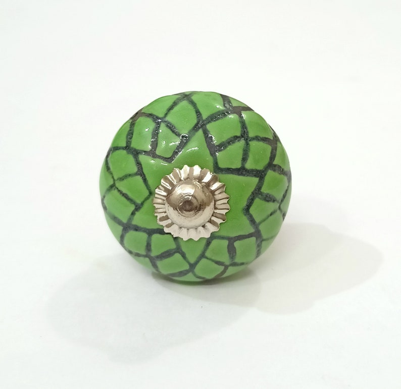 May include: Green ceramic cabinet knob with a black geometric pattern and a silver metal center.