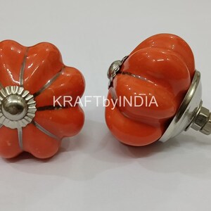 May include: Two orange ceramic pumpkin-shaped knobs with silver accents. One knob has a screw attached.