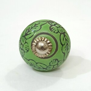 May include: Green ceramic knob with a floral design and a gold metal center.
