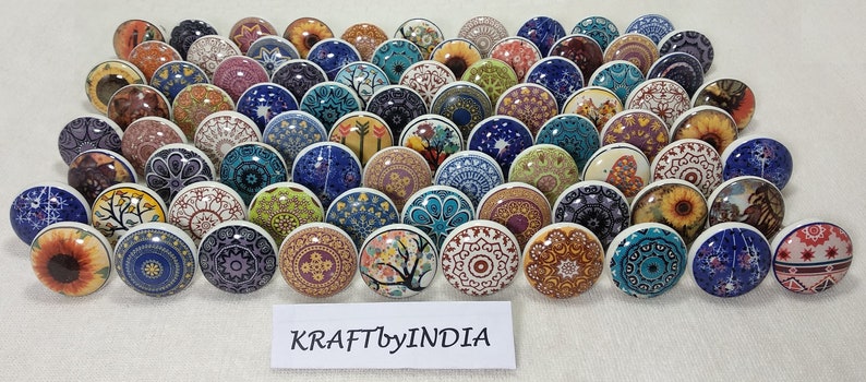 May include: Assortment of 40 colourful ceramic knobs with various patterns, including floral, geometric, and abstract designs. The knobs are approximately 1.5 inches in diameter and have a white base.