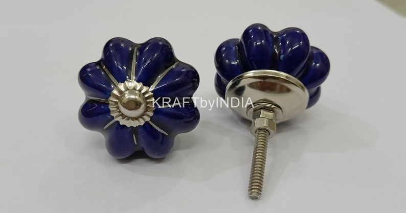 May include: Two blue ceramic cabinet knobs with a silver base and screw. The knobs are shaped like a flower with five petals.