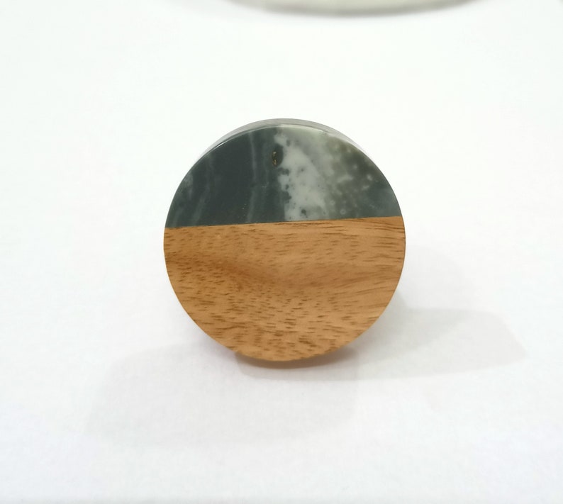 Puede incluir: Un pomo redondo de madera con una parte superior de m&aacute;rmol verde y blanco. El pomo es perfecto para agregar un toque de elegancia r&uacute;stica a cualquier armario o caj&oacute;n.