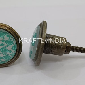 May include: Two antique-style cabinet knobs with a round, teal and white patterned design. The knob on the left has a screw-on back, while the knob on the right has a screw and washer.