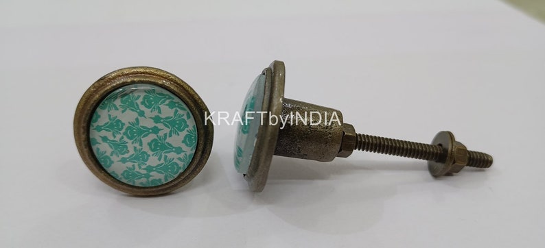 May include: Two antique-style cabinet knobs with a round, teal and white patterned design. The knob on the left has a screw-on back, while the knob on the right has a screw and washer.
