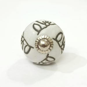 May include: White ceramic knob with a silver metal center and a gray design of stylized flowers.
