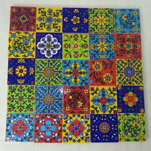Op de afbeelding: Een set van 25 kleurrijke keramische tegels met ingewikkelde bloemmotieven in tinten blauw, groen, rood, geel en wit. De tegels zijn gerangschikt in een rasterpatroon.