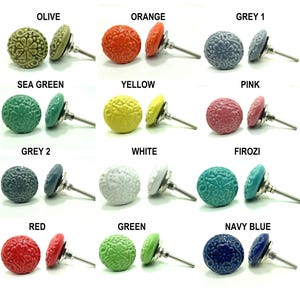 Könnte beinhalten: Eine Sammlung dekorativer Keramik-Schrankknöpfe in verschiedenen Farben, darunter Olive, Orange, Grau, Meeresgrün, Gelb, Rosa, Weiß, Türkis, Rot, Grün und Marineblau. Jeder Knopf hat ein Blumenmuster und einen silbernen Metallstiel.