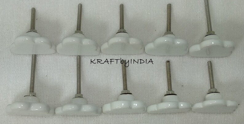 Peut inclure: Dix boutons de porte en c&eacute;ramique blanche en forme de fleur avec des vis argent&eacute;es. Les boutons sont dispos&eacute;s en deux rang&eacute;es de cinq.