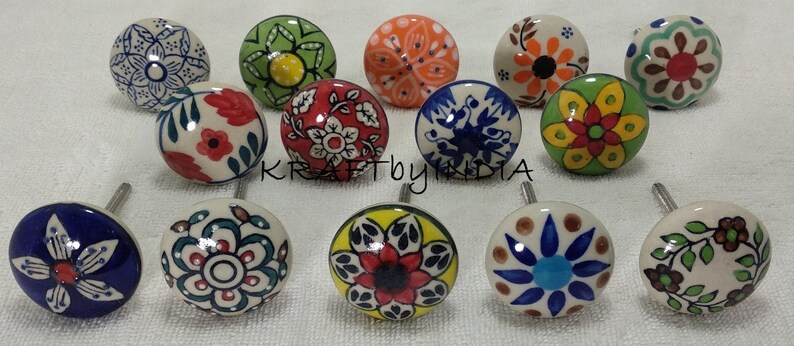 Pode incluir: Conjunto de 12 bot&otilde;es de cer&acirc;mica com v&aacute;rios desenhos florais e geom&eacute;tricos em azul, verde, vermelho, amarelo e laranja. Os bot&otilde;es t&ecirc;m aproximadamente 2,5 cm de di&acirc;metro e um fundo branco.