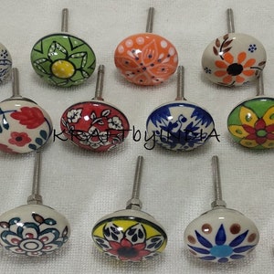 Pode incluir: Conjunto de 15 bot&otilde;es de gaveta de cer&acirc;mica com v&aacute;rios desenhos florais em azul, verde, vermelho, laranja e amarelo. Os bot&otilde;es s&atilde;o brancos com um parafuso prateado.