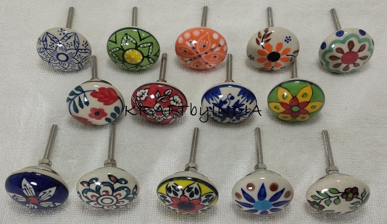 Pode incluir: Conjunto de 15 bot&otilde;es de gaveta de cer&acirc;mica com v&aacute;rios desenhos florais em azul, verde, vermelho, laranja e amarelo. Os bot&otilde;es s&atilde;o brancos com um parafuso prateado.