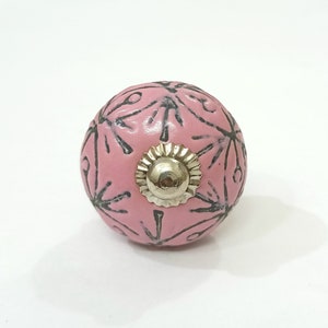 May include: Pink ceramic knob with a silver metal center and a black floral design.