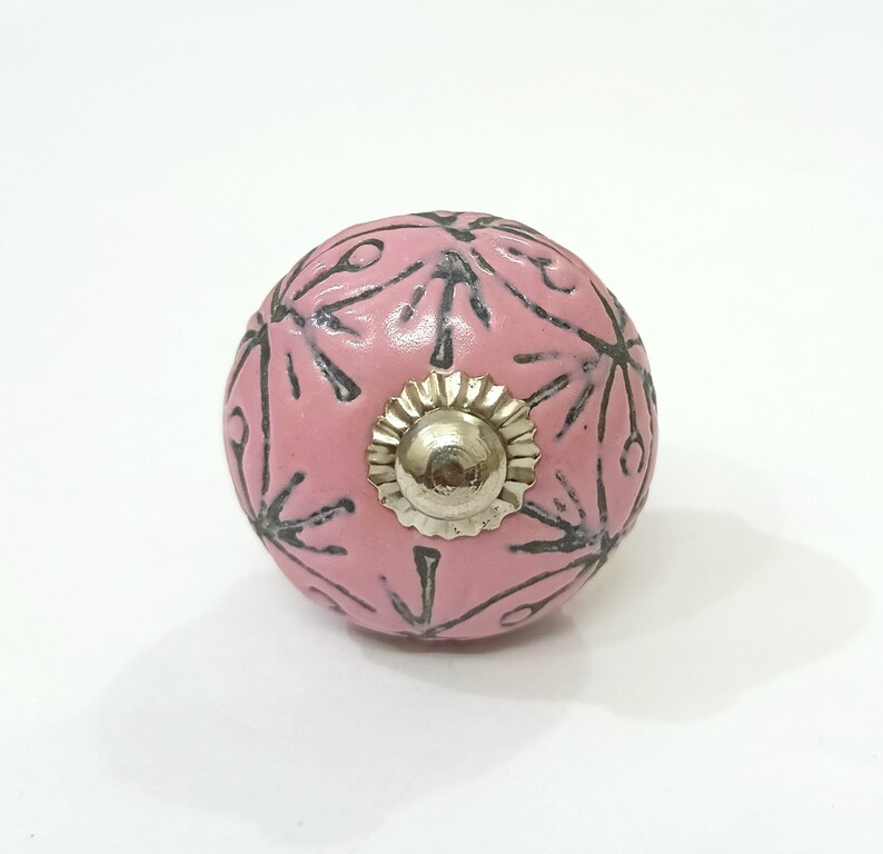 May include: Pink ceramic knob with a silver metal center and a black floral design.