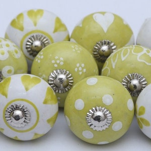 May include: A set of 12 green and white ceramic knobs with various floral and geometric patterns. The knobs have a silver metal base.