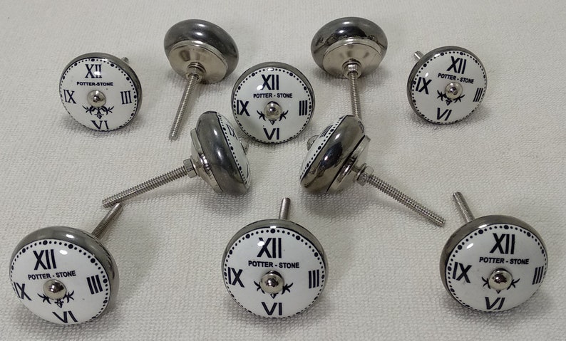 May include: Eight silver and white ceramic clock-face cabinet knobs with black Roman numeral markings and the text "POTTER-STONE".