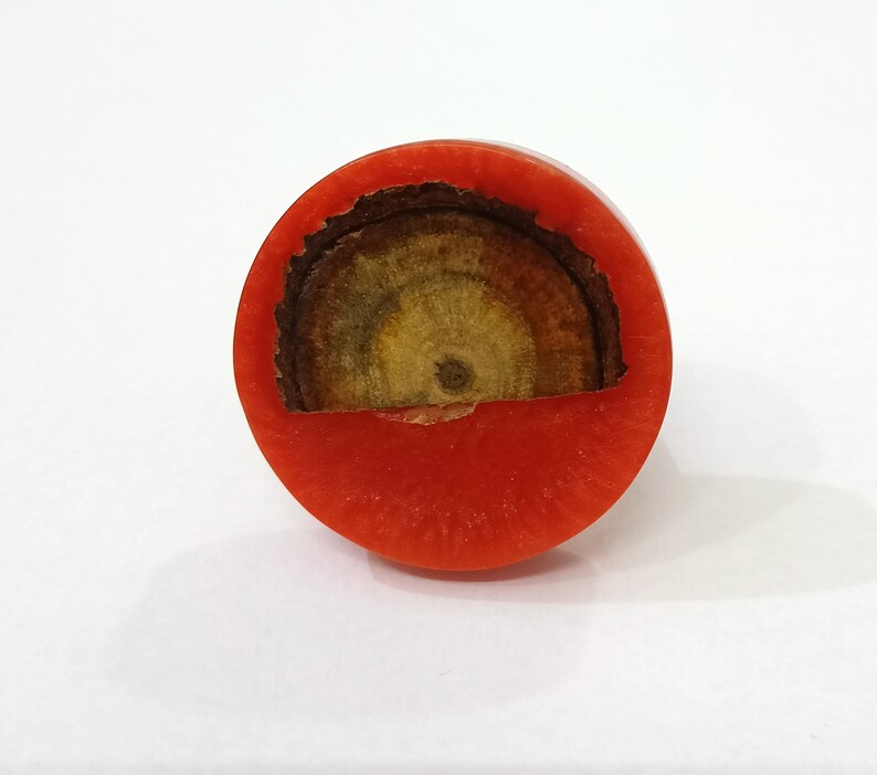 Puede incluir: Un anillo de madera rojo y marr&oacute;n con una abertura circular en el centro. El anillo est&aacute; hecho de madera y tiene un acabado natural.