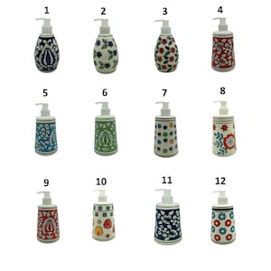 Puede incluir: Una colección de doce dispensadores de jabón o loción de cerámica con tapas de bomba blancas. Cada dispensador presenta un diseño floral o geométrico único pintado a mano en varios colores, incluyendo azul, rojo, verde y amarillo.