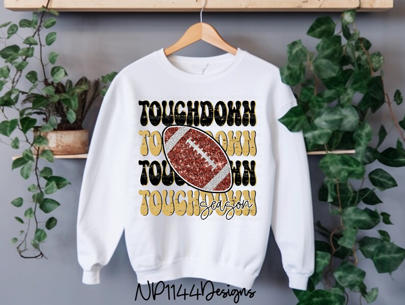 May include: White sweatshirt with a gold and black graphic that says "Touchdown Season" with a football in the center.