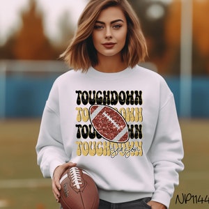 May include: White sweatshirt with a gold and black graphic that says "Touchdown Season" with a red and black football graphic in the center.