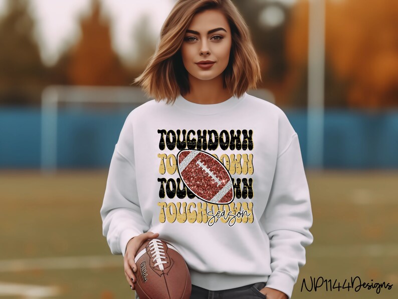 May include: White sweatshirt with a gold and black graphic that says "Touchdown Season" with a red and black football graphic in the center.