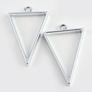 May include: Two silver triangle-shaped metal frames with a loop at the top for hanging. The frames are empty and ready for crafting.
