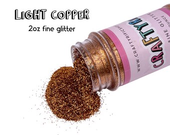 May include: A 2 oz bottle of light copper fine glitter, spilling out onto a white background. The bottle is labeled "CRAFTY" and "www.CRAFTYTRIFICS.com".