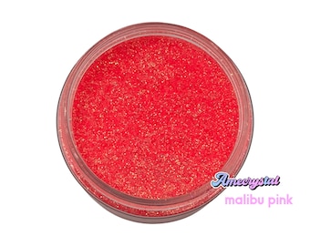 May include: A close-up of a jar of bright pink glitter. The glitter is fine and shimmery, and the jar is clear glass. The text "Amecrystal malibu pink" is printed on the label.
