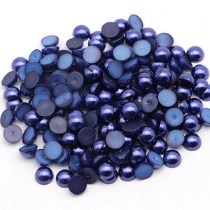 May include: A large pile of dark blue pearl beads. The beads are round and have a smooth, shiny finish.