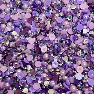 May include: A mix of purple, lavender, and iridescent round and flat embellishments. These decorative beads are perfect for crafting and adding sparkle to projects.