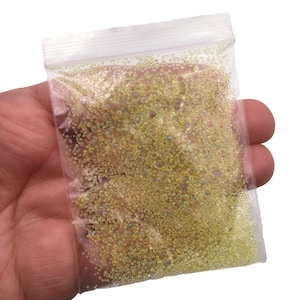 May include: A clear plastic bag filled with small, iridescent yellow beads. The beads are various sizes and have a pearlescent finish.