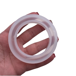 May include: A white silicone ring mold for resin crafts. The mold is circular with a raised lip around the edge.