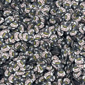 May include: A large pile of black and white cartoon face charms with yellow and pink accents. The faces have a mustache and a crown.