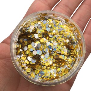 May include: A clear plastic jar filled with gold and silver glitter. The glitter is in the shape of small circles.