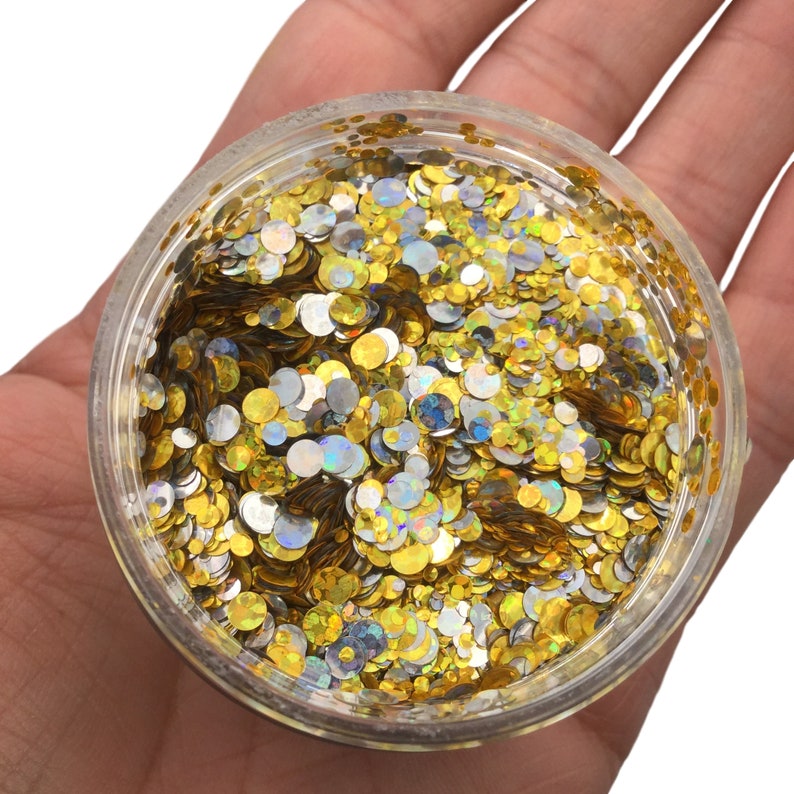 May include: A clear plastic jar filled with gold and silver glitter. The glitter is in the shape of small circles.
