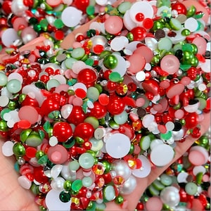May include: A large assortment of red, white, and green Christmas-themed embellishments. The embellishments include round, flat, and pearlescent shapes.